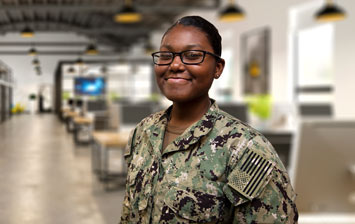 Smiling soldier standing in front of a row of desks