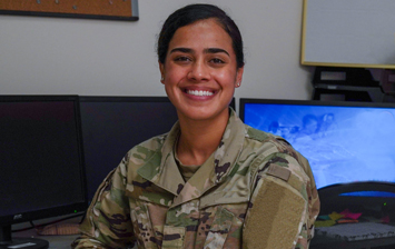 Soldier sitting in front of computer monitors smiling